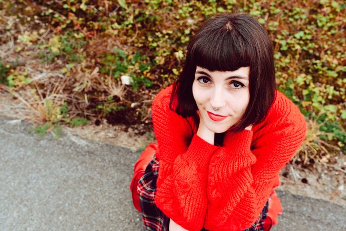 Woman sitting on red suitcase on road