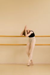Ballet dancer leaning back with arms raised at barre