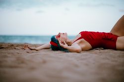 Relaxed woman in bright stylish swimsuit lying on sandy beach