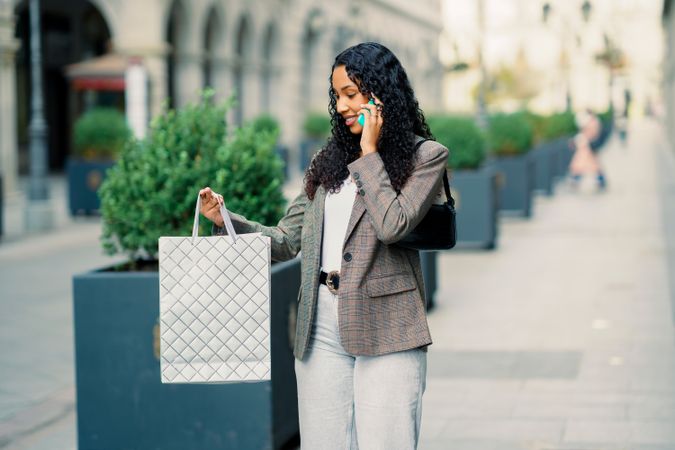A fashionable woman engaging in shopping via her phone, surrounded by a lively urban backdrop