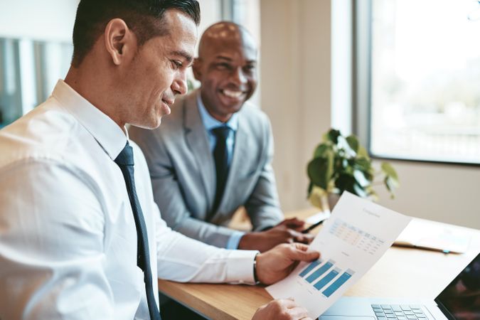 Man reviewing chart with smiling colleague