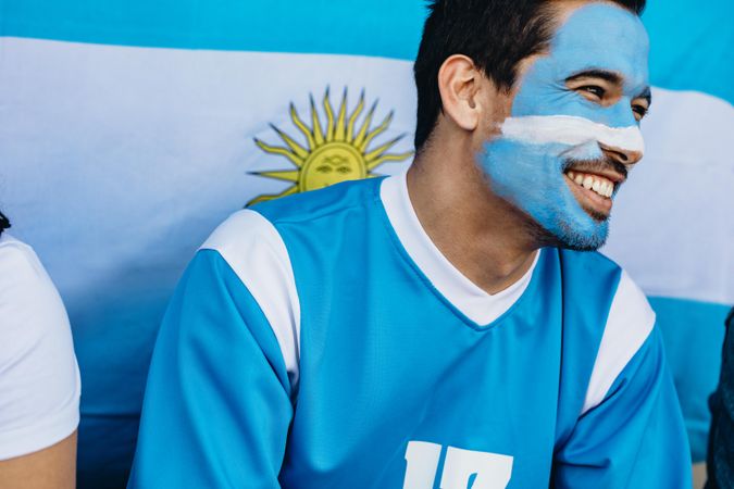 Devoted fan with Argentina flag behind in soccer stadium