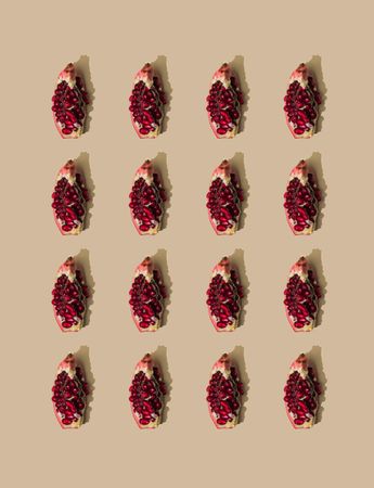 Pattern of pomegranate fruit slices and pastel sand background