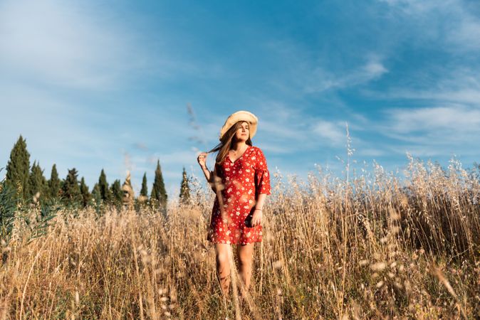 Happy dreamy woman standing among high grass