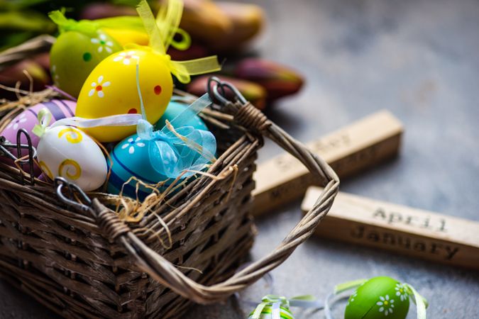 Decorative Easter eggs in basket on table