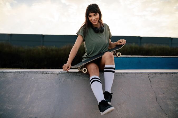 Woman skateboarder sitting outdoors in a skate park