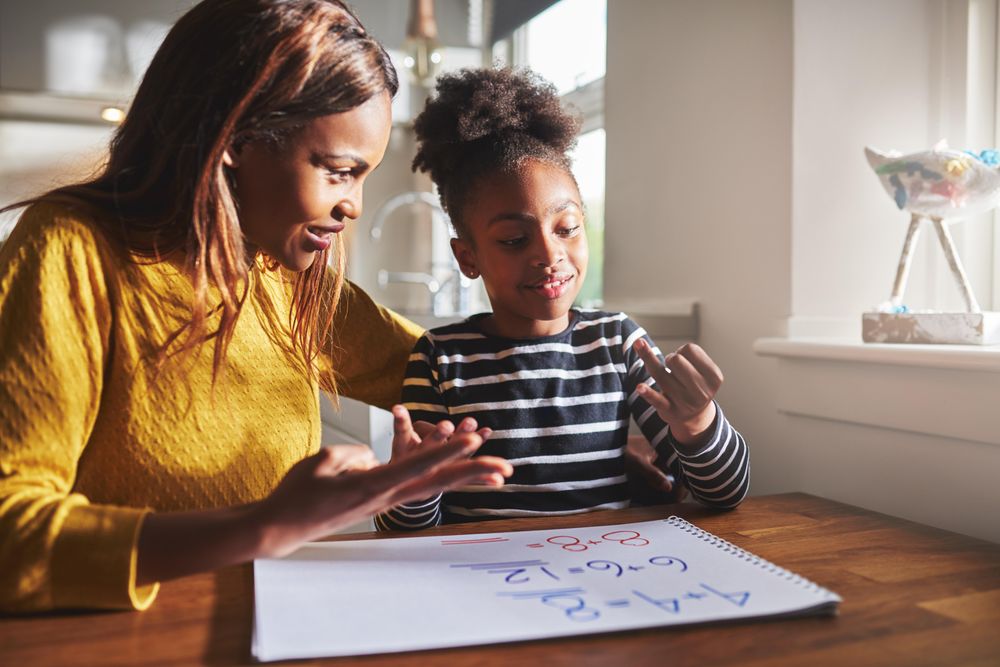 Smiling mother helping daughter do math equations