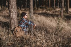 Relaxed tourist resting by tree in forest