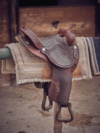 Saddle against shabby wooden stable