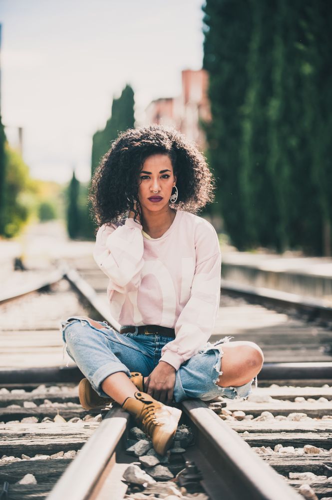 Black woman looking at camera in the tracks of a train
