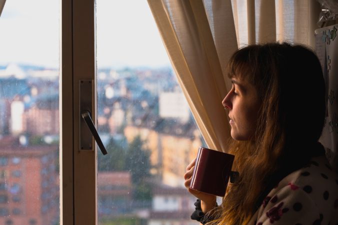 Woman enjoying hot beverage near fridge