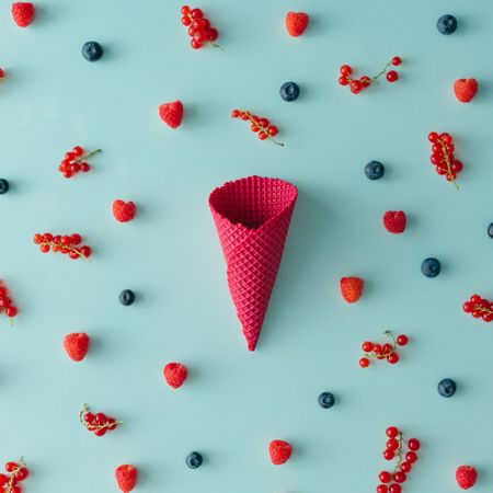 Red waffle cone on blue background with berries