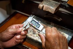 Jeweler hands measuring and checking gold jewel size with vernier caliper tool. Goldsmith working creating in his jewelry workshop.