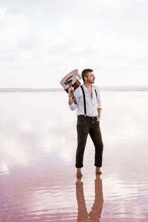 Inspired musician holding guitar at seaside