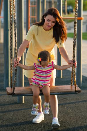 Toddler girl and mom on swing