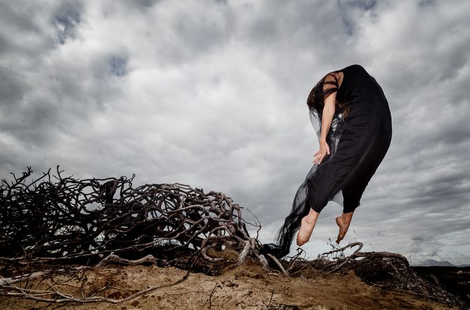 Woman posing in air near dry twigs and blue sky