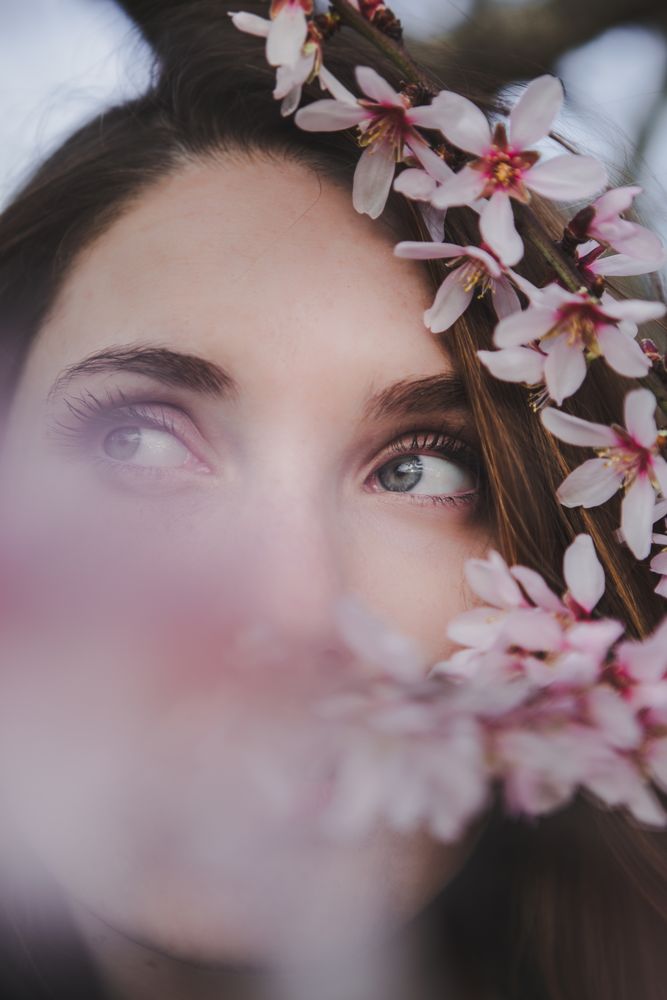 Young woman near tree twig with flowers