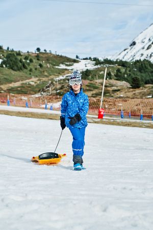 Kid with sleigh walking on snow