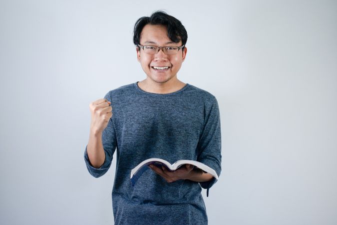 Asian student holding books and making strong gesture