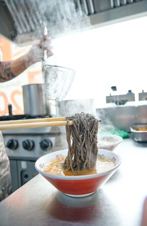 Cook making spicy Japanese soup with noodles
