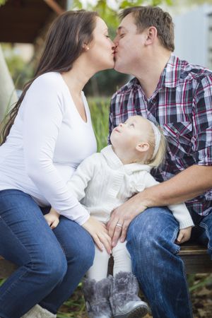 Happy Pregnant Couple Kisses as Baby Girl Watches