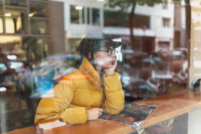 Stylish woman with magazine sitting in cafe