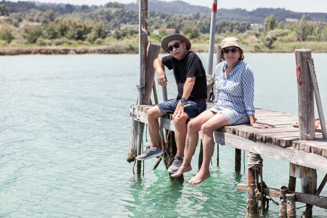 older couple sitting on dock dangling with legs