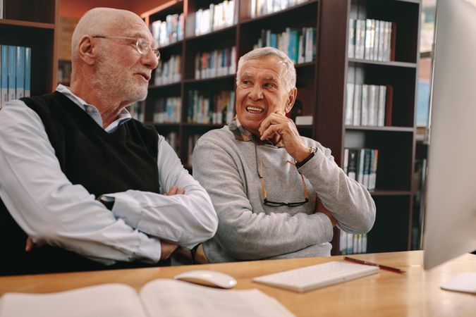 Two mature males talking after lecture in library