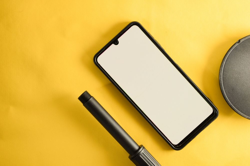 Mock up phone & circular accessory on yellow table with copy space