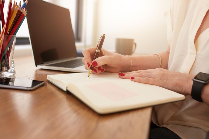 Close up image of woman sitting at her desk and writing notes