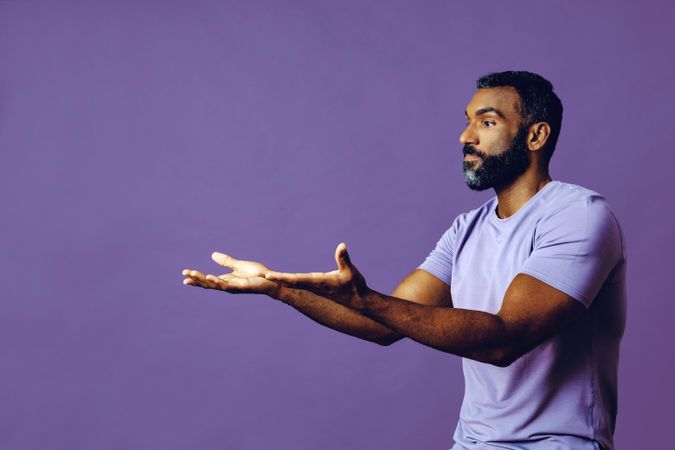 Side view of male in purple studio with hands gesturing at copy space