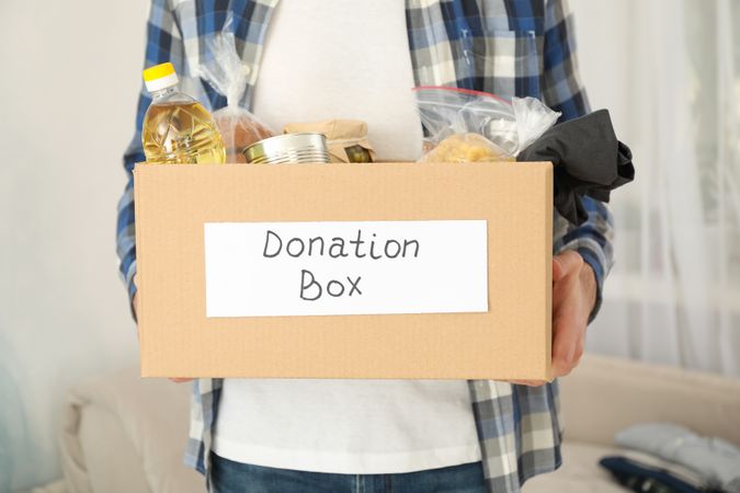 Young man holds donation box. Volunteer. Covid 19