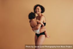 Woman laughing with her eyes closed while holding her child bGlEX0