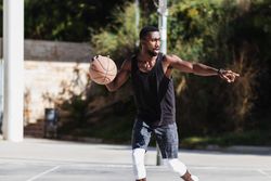 Black man playing basketball on sports ground