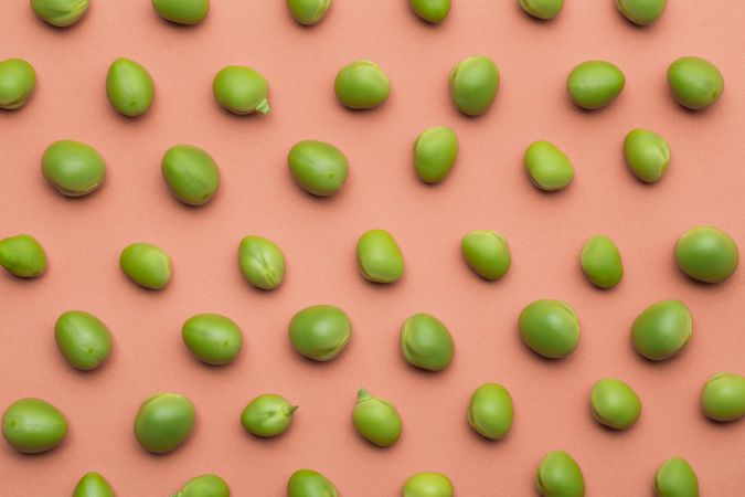 Set of peas placed orderly on salmon colored background