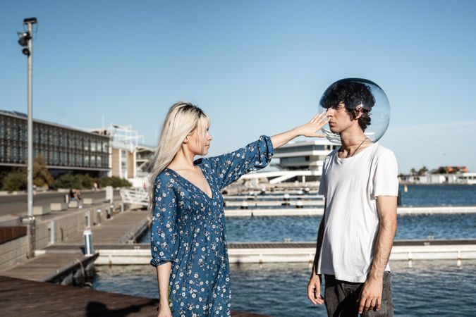 Woman touching fish bowl on head of boyfriend