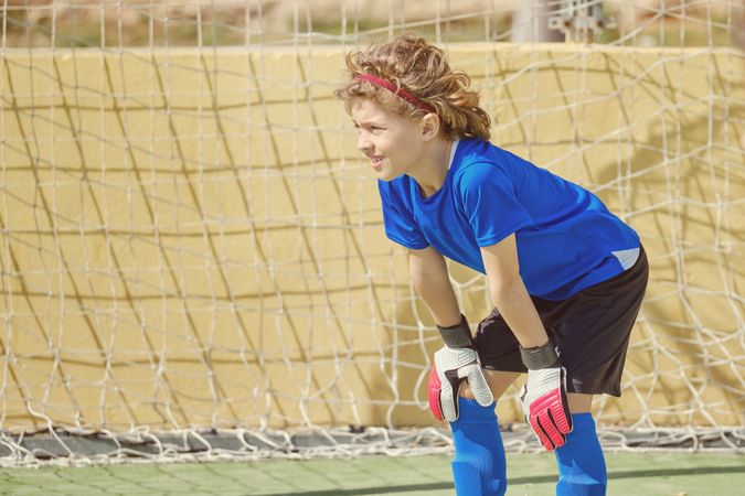 Serious kid standing at football goal