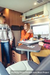 Women in warm sweaters having breakfast in back of van, vertical 0PQL75