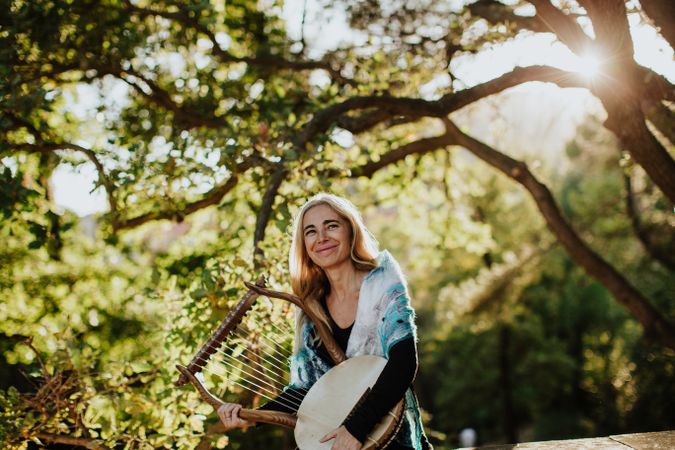 Cheerful charming woman with lyre in garden