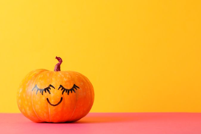 Pumpkin with smile against yellow background, space for text