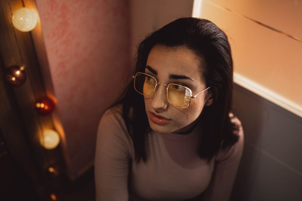 young woman portrait with yellow glasses posing