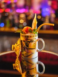 Cup of cold cocktail decorated with fruits and mint leaves