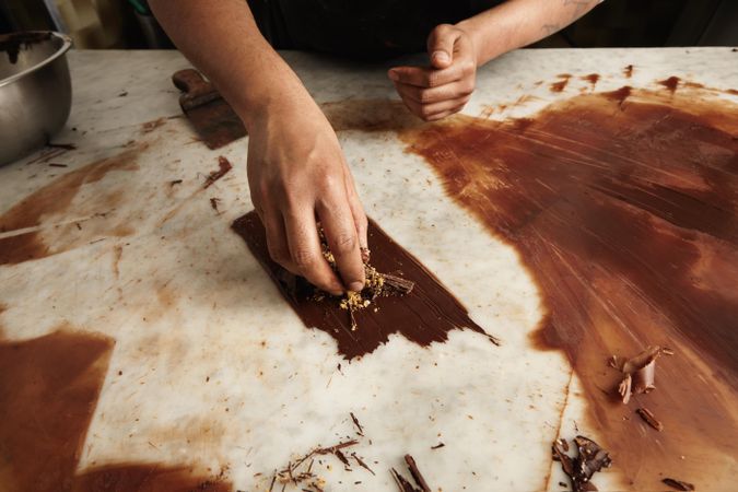 Picture of hands putting ground nuts on melted chocolate