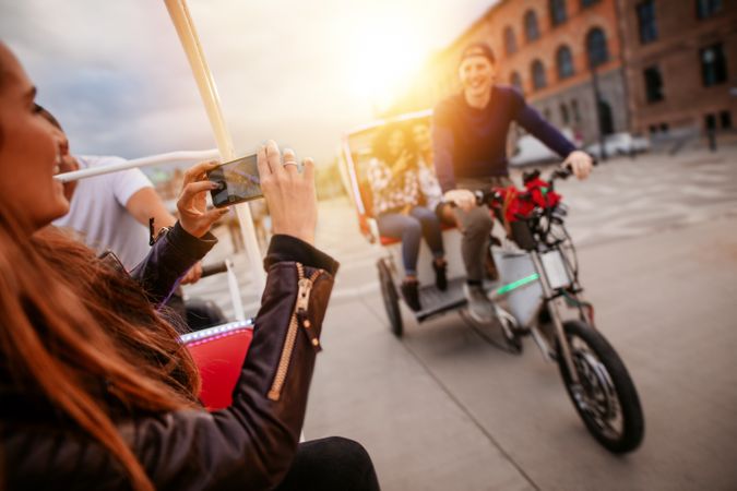 Woman photographing friends on tricycle ride