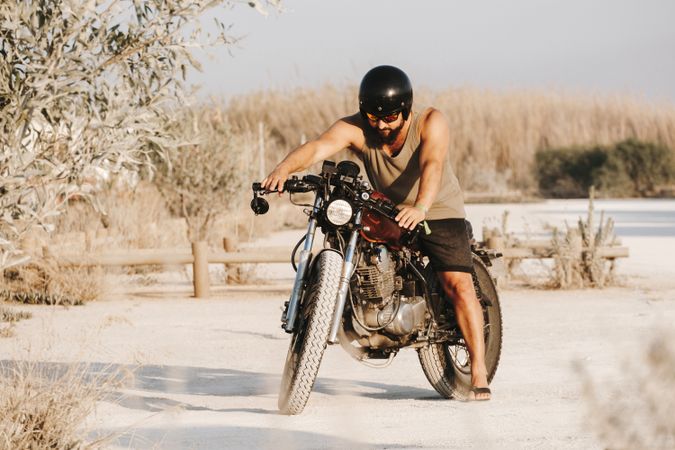 Serious male driving motorcycle in forest