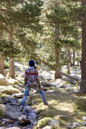 Woman standing over small stream of water in green woods