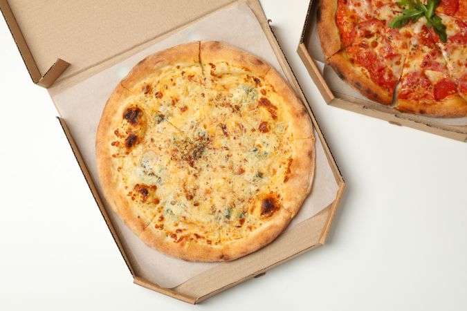Two pizza in carton boxes on neutral background