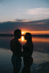 Couple hugging on beach of lake at sunset