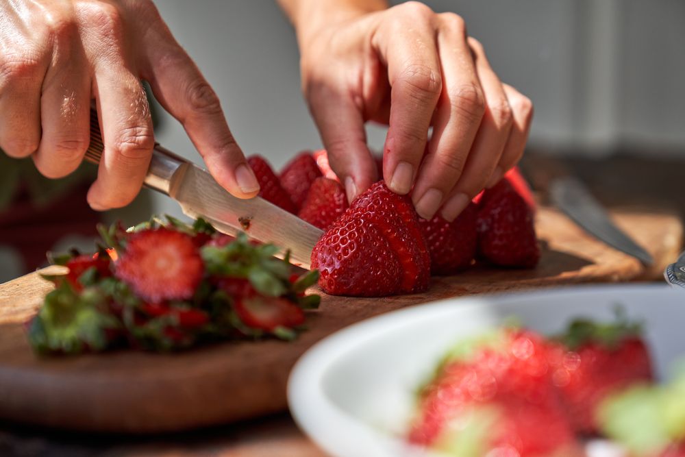 Crop cook cutting strawberry with knife