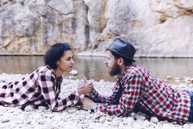 Positive woman and man resting on stone shore near river